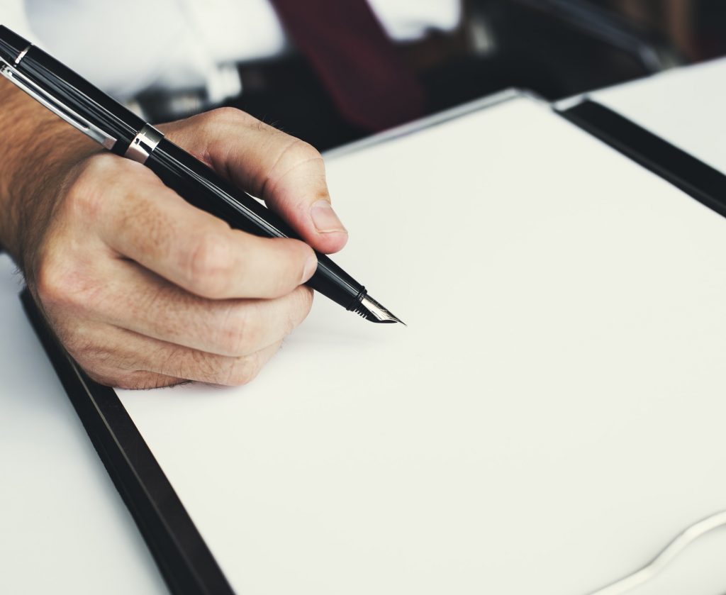 Closeup of hand with fountain pen over blank paper